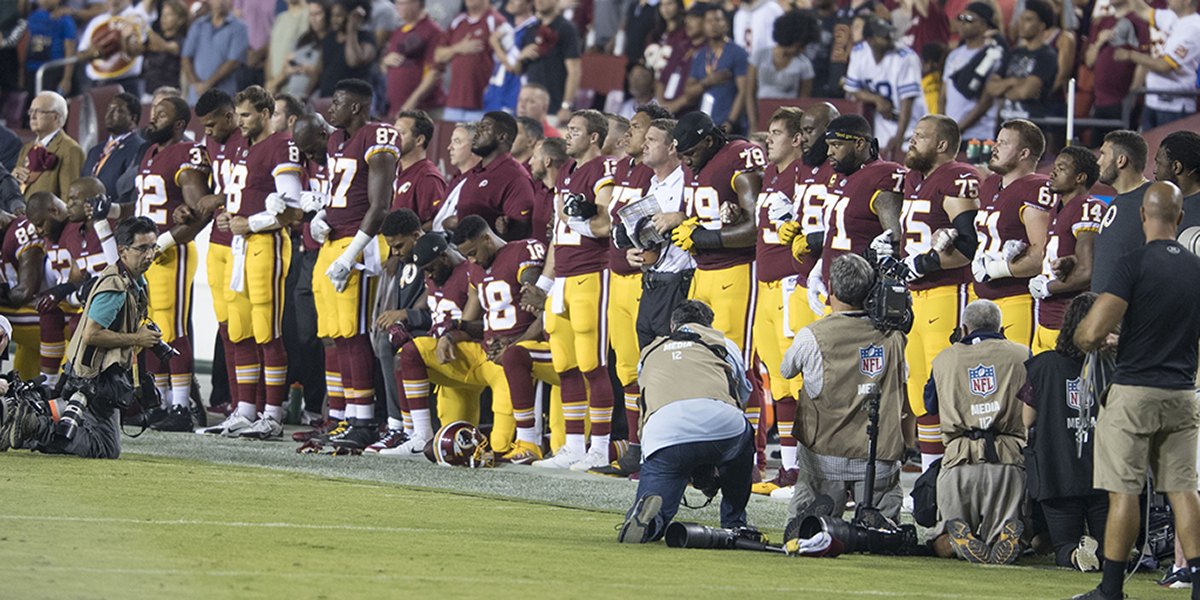 Photo of Washington NFL players locking arms, kneeling during national anthem